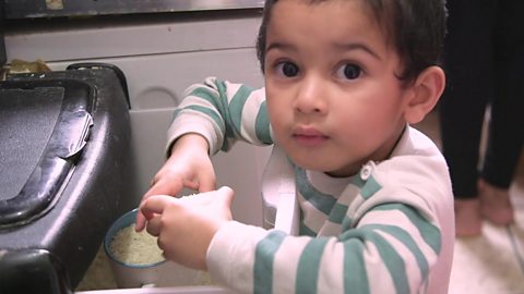 A little boy with a cup of rice.