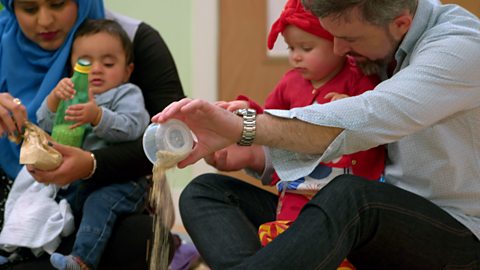 2 babies and their parents playing with porridge oats at the Baby Club.