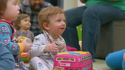 Young girls sits on the floor on the Baby Club, smiling