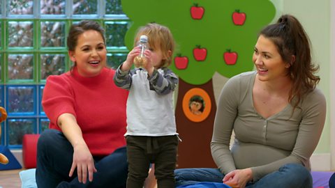 Giovanna Fletcher helps a toddler and their mum play with a homemade rattle