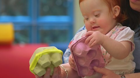 A baby playing with two egg cartons