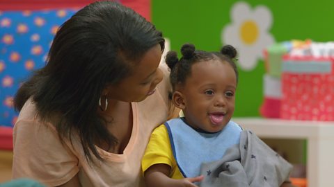 A young baby and her mum play with a scarf with stars on.