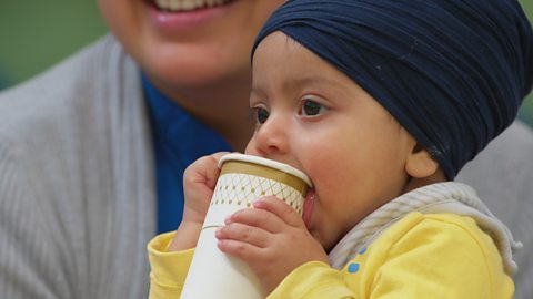 A baby sipping from a paper cup