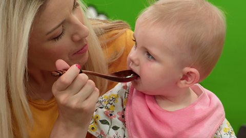 A parent pretends to feed her baby with a wooden spoon