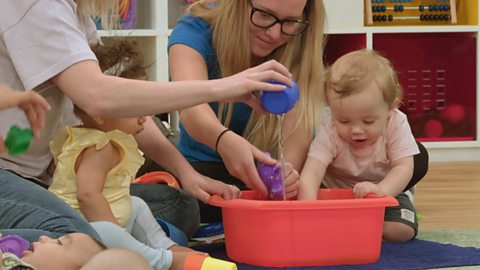 Parents playing with their babies in a tub of water