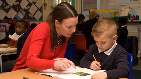 Teacher helping child with school work at desk