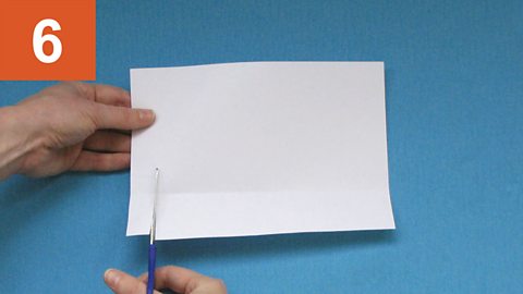 Step 6: Scissors cut upwards in a straight line towards a fold line in paper