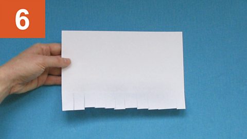 Step 6: Hand holds a sheet of paper with a fringed edge