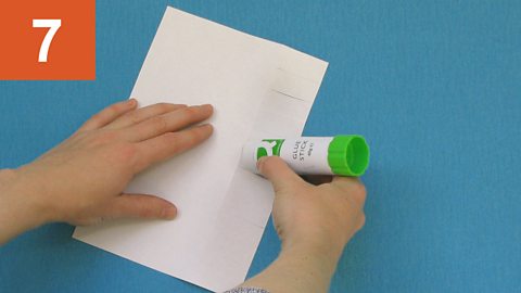 Step 7: Hand puts glue on fringed strips of a sheet of paper