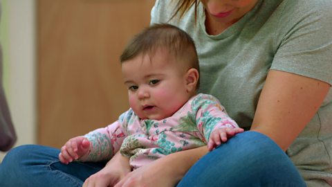 A baby girl being sang to by her mum.