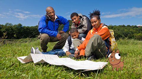 A family walking in the countryside is looking at a map of the local area