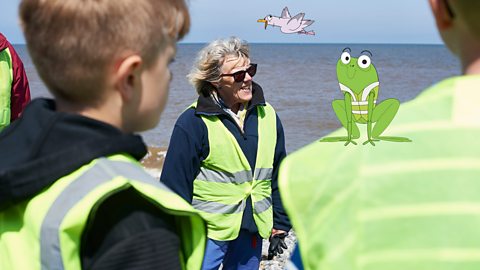 A group of young people with grown-ups wearing bright vests while doing fieldwork.