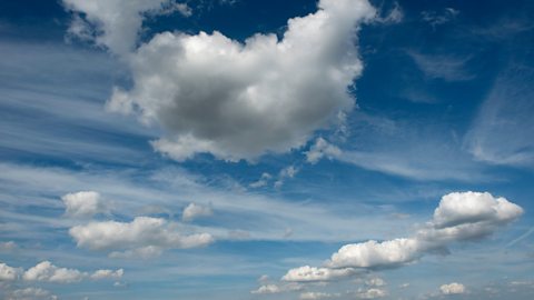 Several fluffy clouds float against a blue sky 