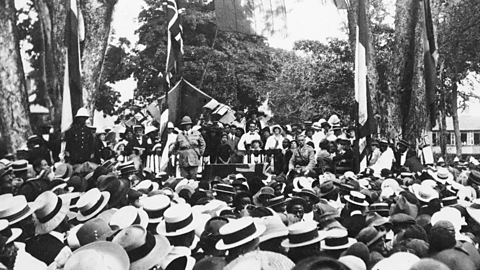 Photo - a man speaks on stage at a recruitment rally. 