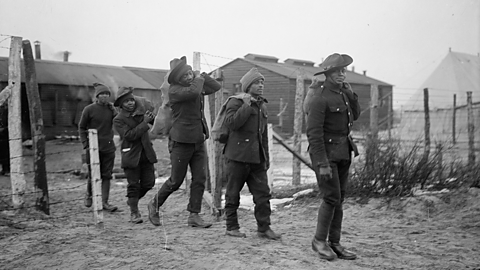 SANLC members carrying sacks of firewood in a camp.