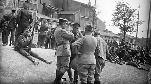 White officers stood and sat in a town during World War One. 