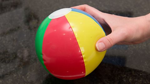 A hand holding a small inflatable beach ball