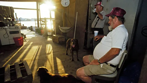 Two men and their dogs wait for the morning catch at the Clam House, Ocracoke Island, North Carolina.