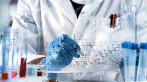 Person doing science experiment - plotting results on a graph - test tubes to left