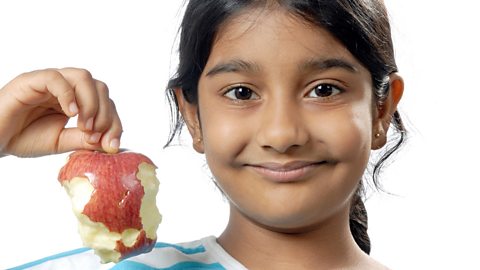 A girl holds a half-eaten apple