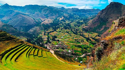 A mountain region in Peru. The mountains are tall and brown, with some grass.