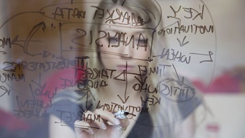 Woman making prediction by writing on glass with a black marker.