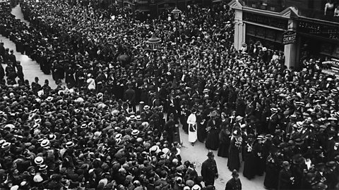Large crowds of people on either side of the street at the funeral of Emily Davison. 