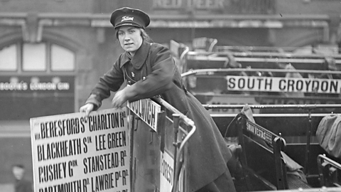 A female bus conductor and member of the Women's Auxiliary Army Corps changes the destination sign on her bus.