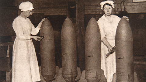 Female munition builders, known as Munitionettes, stand alongside the munitions they have built. 
