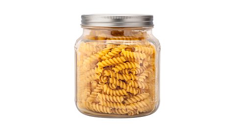 A glass jar containing raw pasta