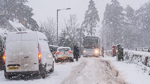 A van, a car and a bus stuck in heavy snow.