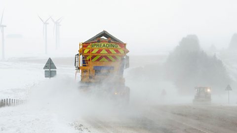 A gritter on a motorway in heavy snow.