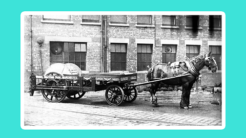 A horse and carriage stationary in a cobbled railway yard.