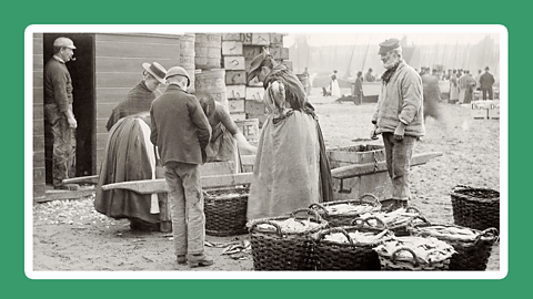 Fishermen on the beach selling baskets of mackerel