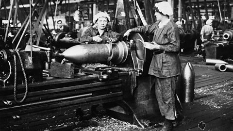 Female munition workers cutting copper bands for shell cases and oiling the machinery in a Birmingham factory, March 1918.