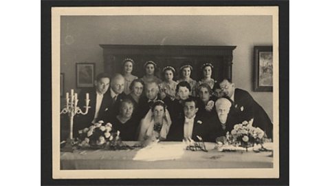 A black and white photograph of a newly married couple and their wedding guests.