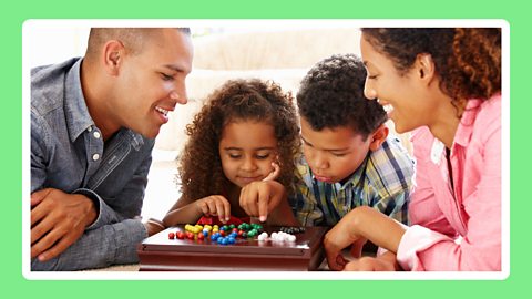 Children playing a board game with their family.