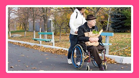 A lady helping a man in the wheelchair 