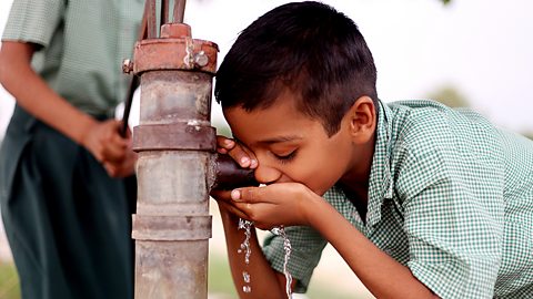 A thirsty child drinking water on water pump