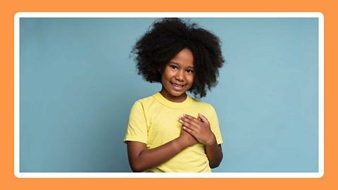 A child putting their hands over their heart. 