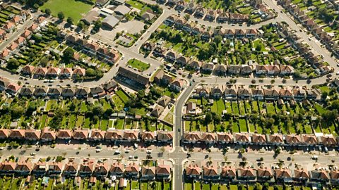 An aerial view of a suburban housing estate with lots of houses, roads and gardens