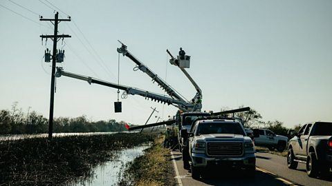 Repairmen on a complex vehicle repairing damaged powerlines.