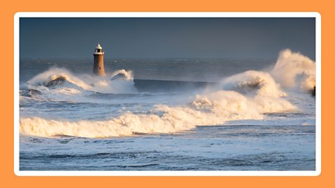 Lighthouse with waves crashing around it.