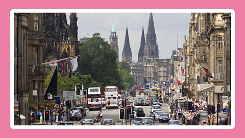 Main road with buses cars and people in Edinburgh.