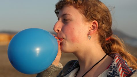 A photo of a person blowing up a balloon.