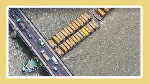 Cargo ship going under a road bridge on the River Thames.