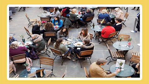 People sat around tables outside having food and drinks.