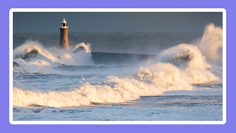 Lighthouse and waves crashing on the shore.