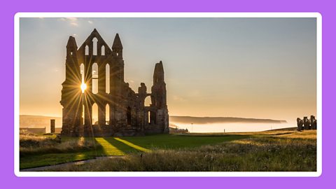 Whitby Abbey with the sun setting behind it.