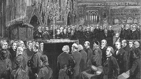 A balck and white illustration of the inside of Westminster Abbey during Darwin's funeral. A crowd of people, mainly men, are surrounding Darwin's coffin raised on a plinth. 